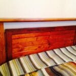 Custom headboard built with reclaimed lumber from demolished camp